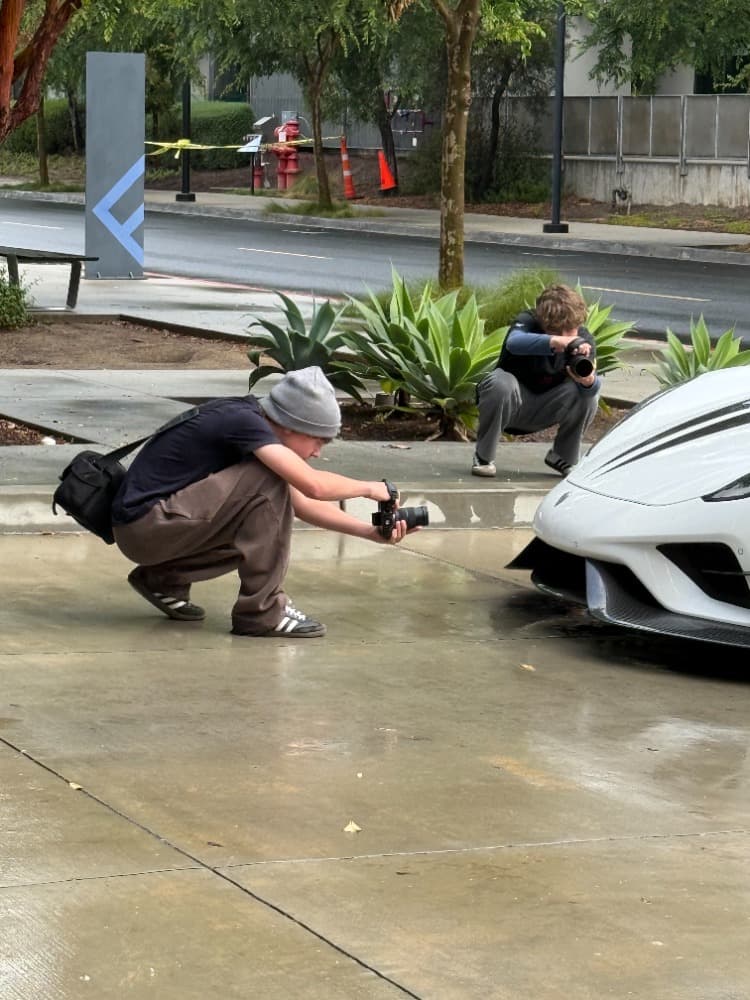 Both brothers crouched down shooting a sports car